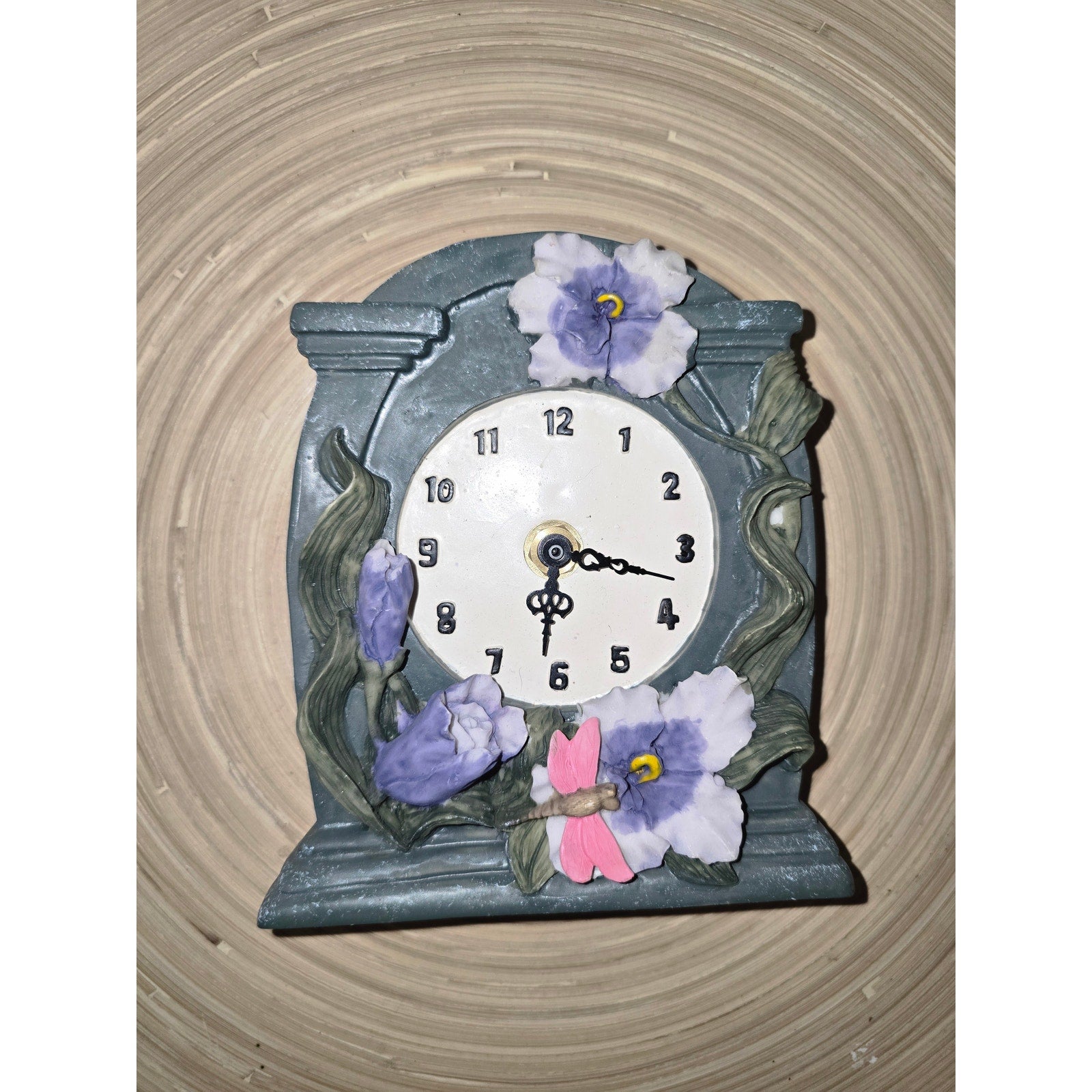 This decorative, hand-painted ceramic or resin tabletop clock